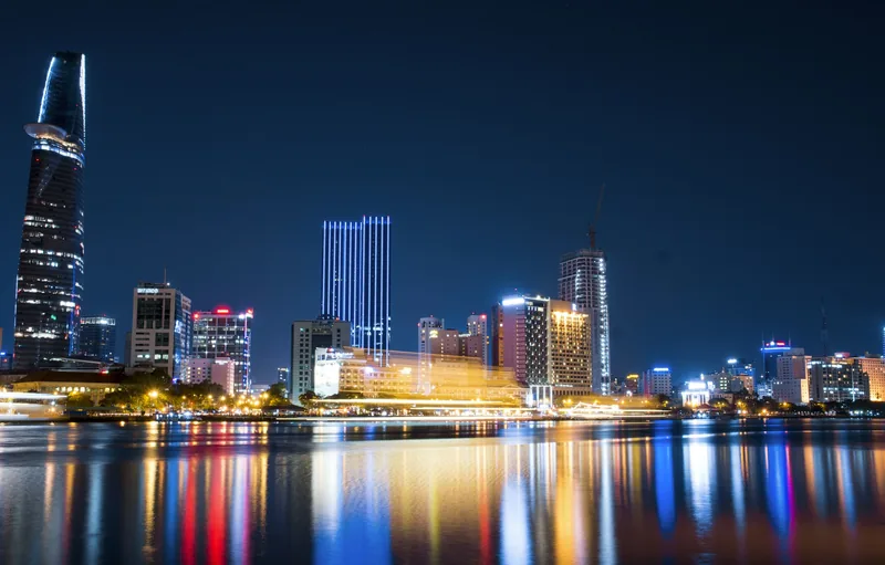 The Ho Chi Minh City skyline at night, lit up over the Saigon River